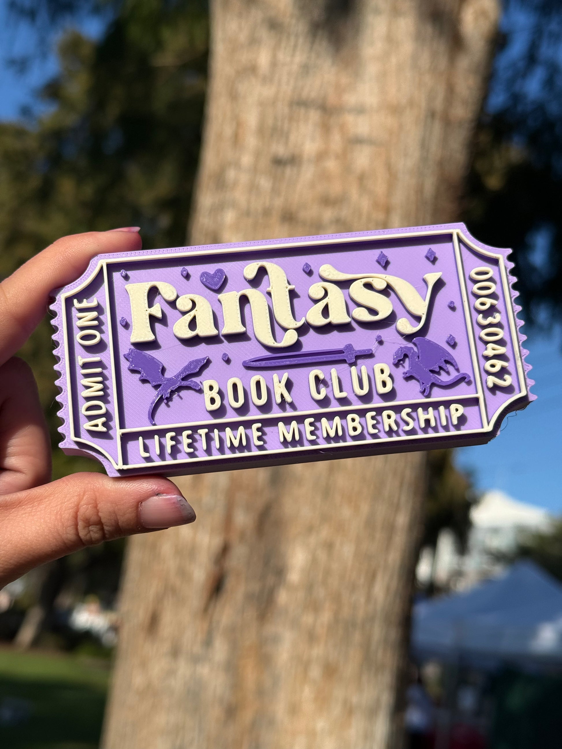A purple 3D printed theater ticket to 'Fantasy Book Club' with 'Admit One', 'Lifetime Membership', and the numbers '00630462' written on the edges